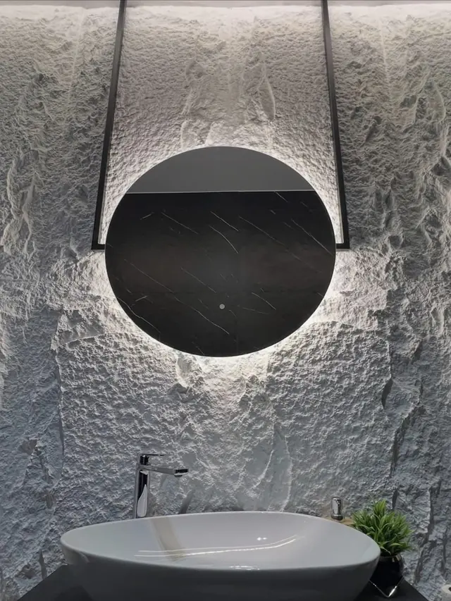 Bagno con parete in rilievo e specchio rotondo retroilluminato