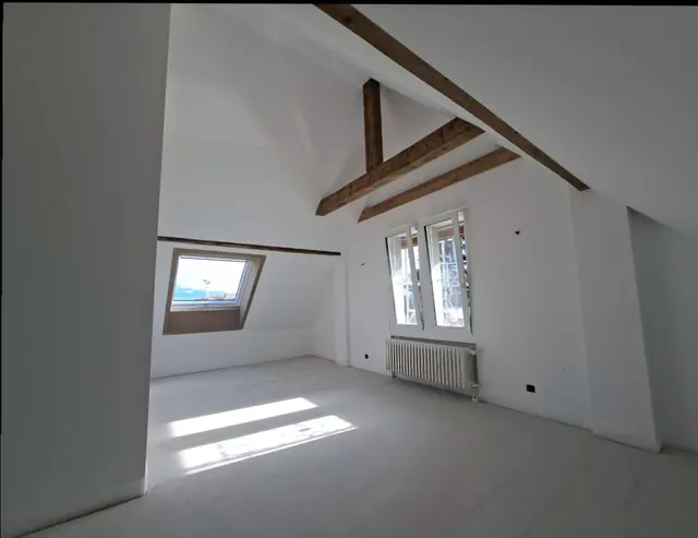 Sottotetto ristrutturato con travi a vista e finestra da tetto