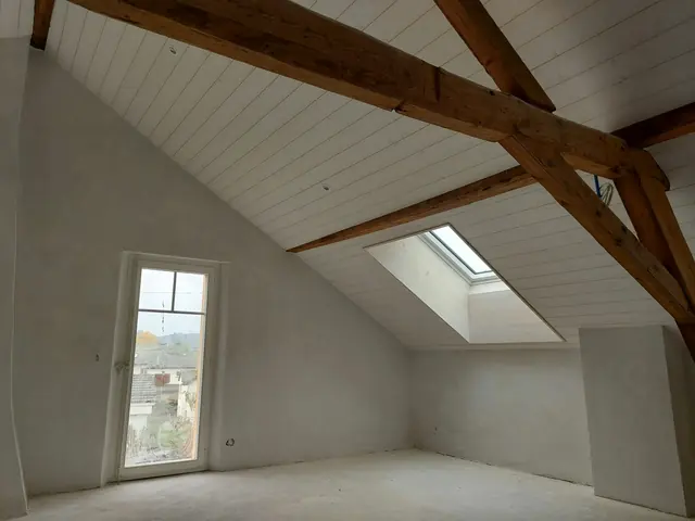 Attic with plastered walls, white panelling and a large window